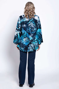 Back view of woman in blue and black abstract print blouse and navy pants