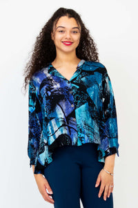 Woman wearing a blue and black abstract print cropped blouse with hi-lo hem, front view