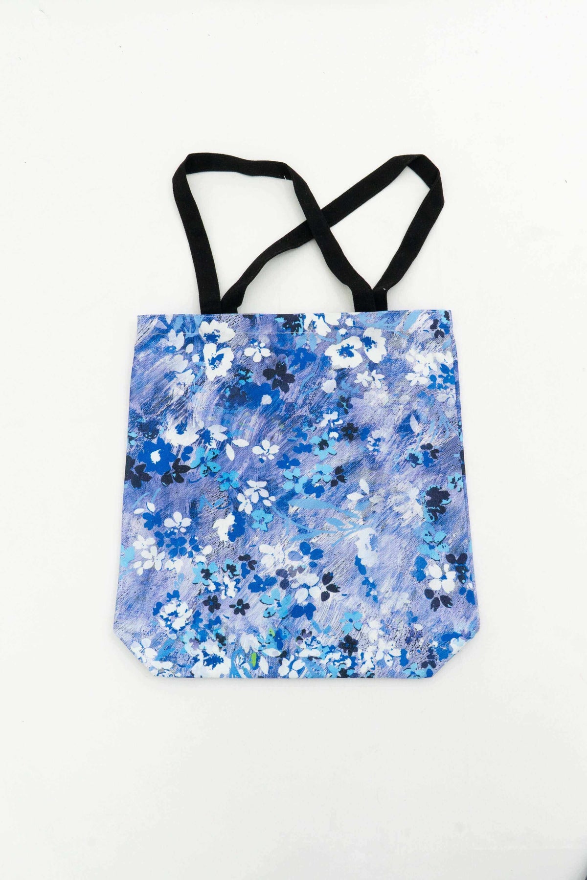 Reusable tote bag with blue and white floral print and black handles