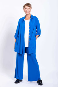 Woman in blue blouse-jacket with hands in side seam pockets over white top