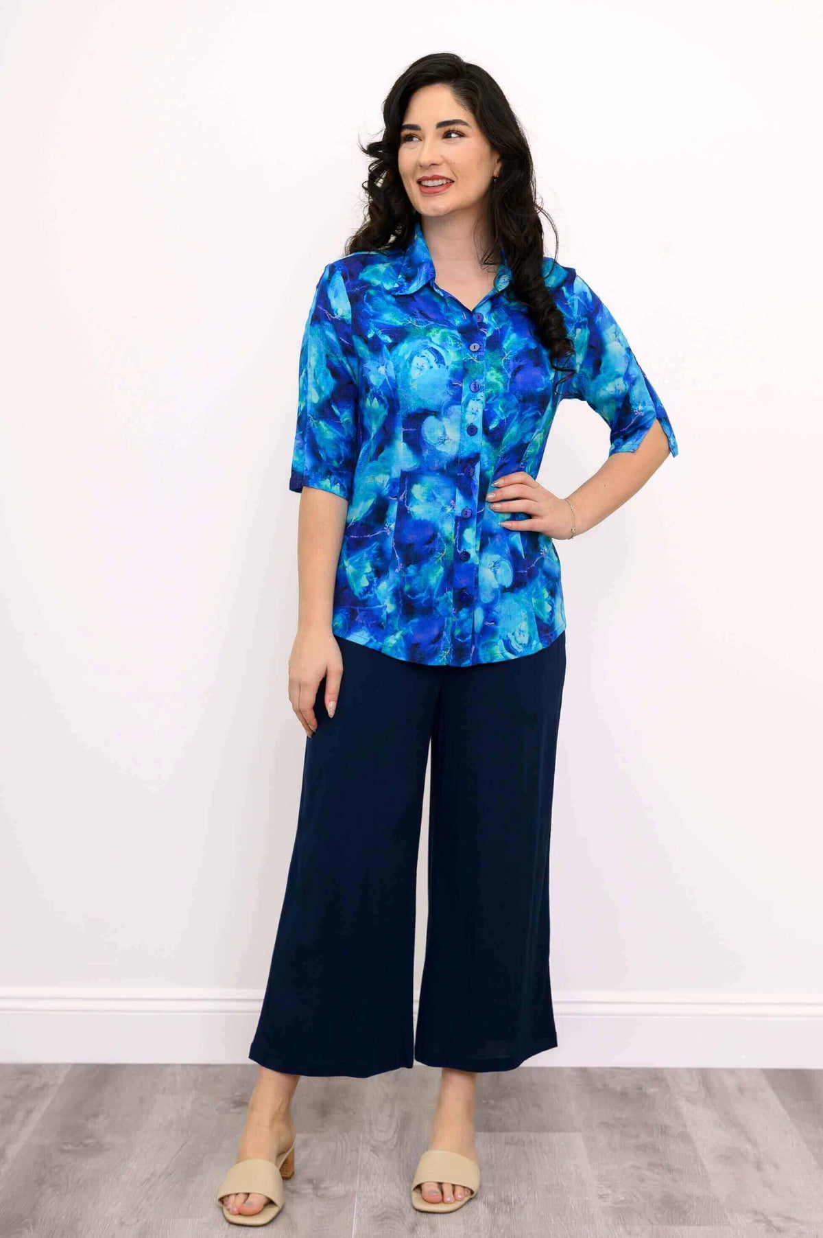 Model in a blue blouse styled with navy culottes and beige sandals