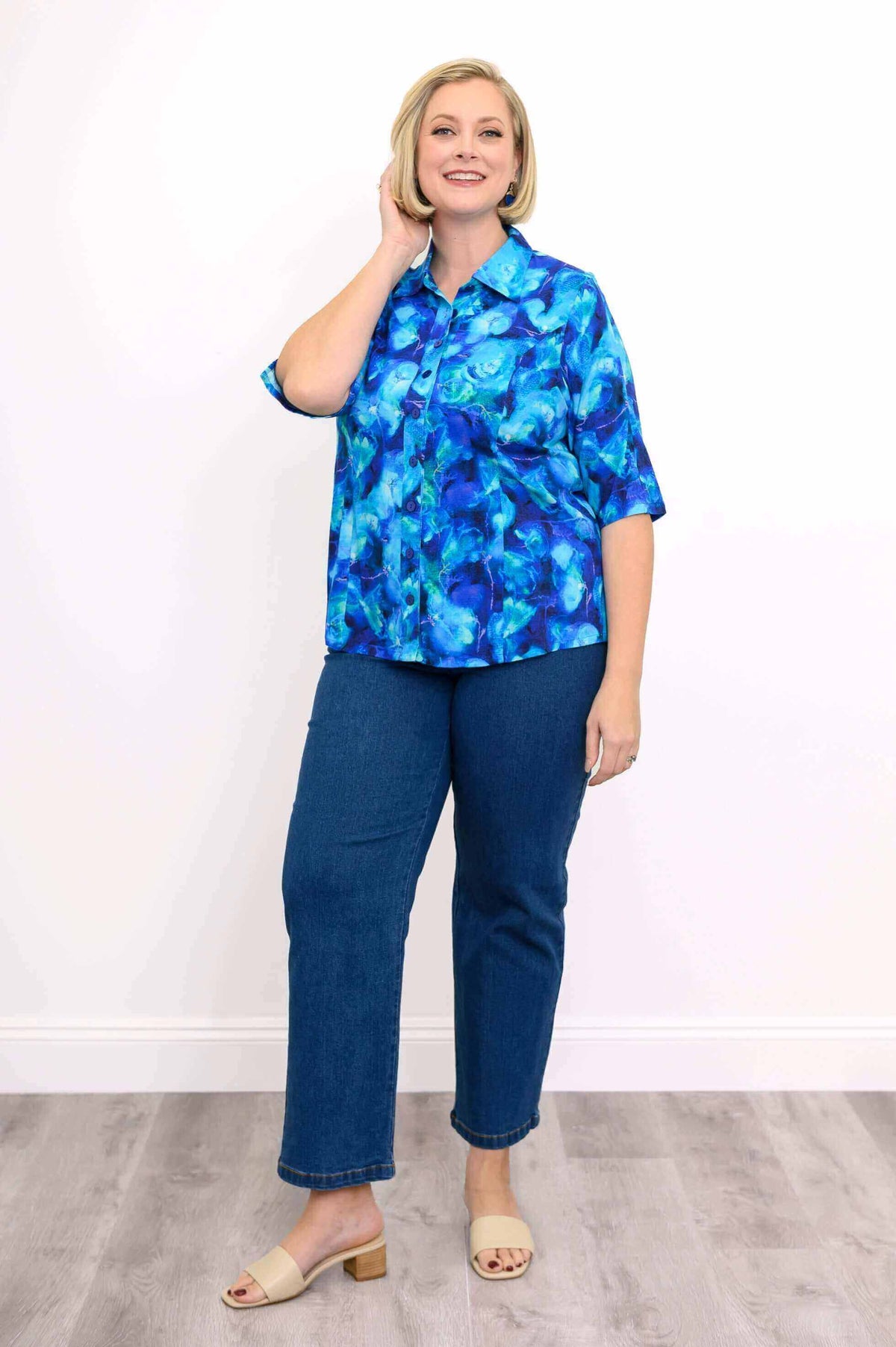 Model in a blue blouse styled with straight-leg denim jeans and beige sandals
