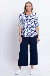 Woman standing in a blue dapple dot print blouse with wide-leg navy pants