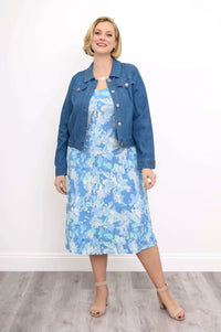 Woman styled in a blue denim jacket over a blue and white floral dress