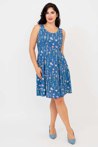 Angled front view of woman in blue floral sleeveless A-line Sara dress with tie-belt waist