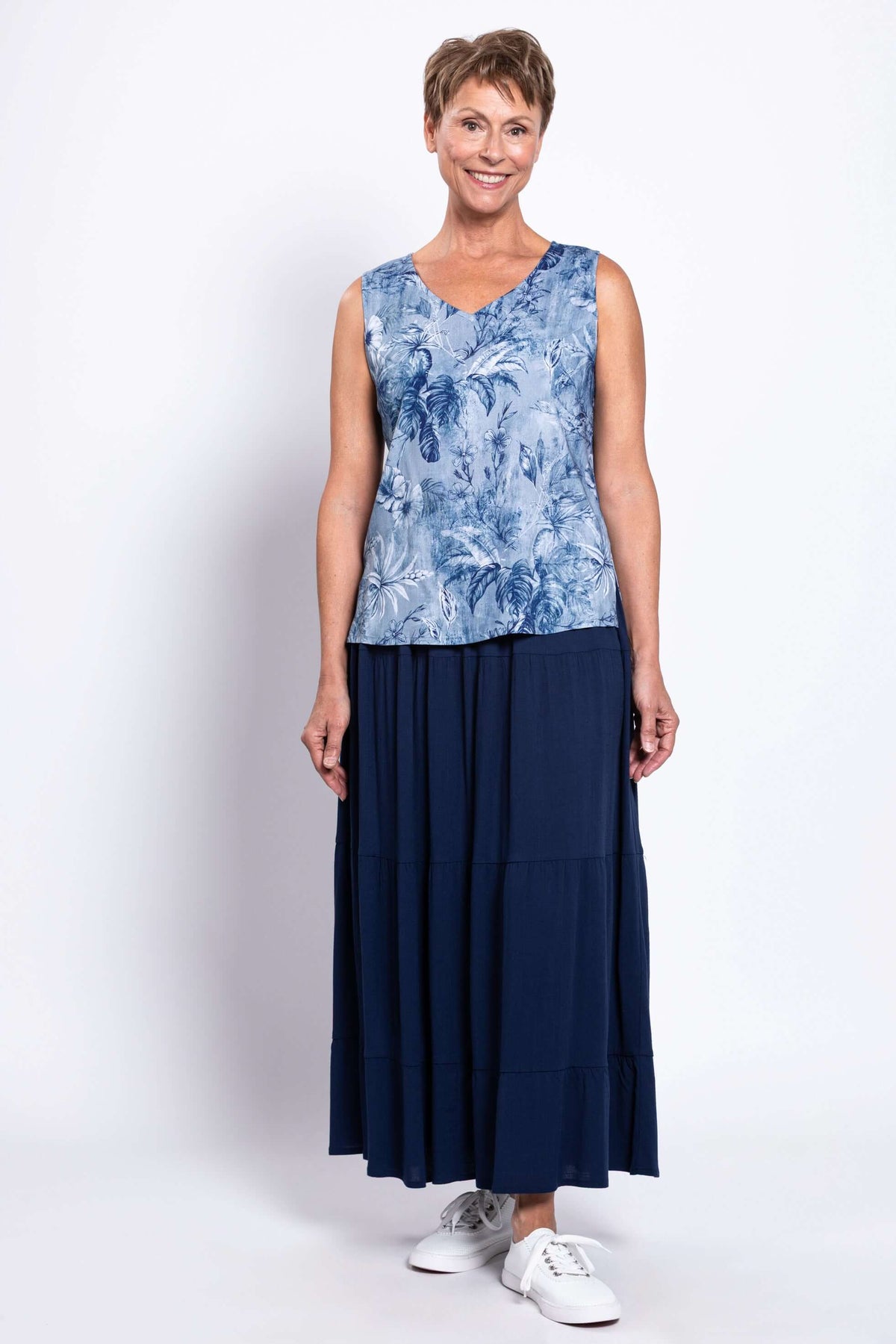 Older woman in a blue floral V-neck tank top paired with a navy maxi skirt and sneakers