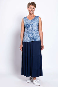 Older woman in a blue floral V-neck tank top paired with a navy maxi skirt and sneakers