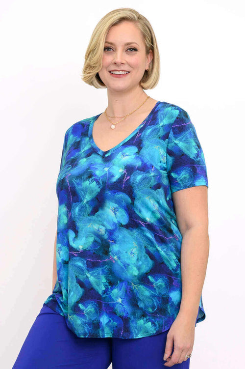 Woman wearing a blue floral bamboo V-neck top with short sleeves, smiling