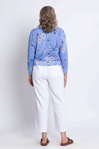 Back view of woman in a blue floral cardigan and white pants