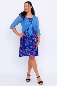 Model posing in blue floral dress with blue knit cardigan tied at the waist