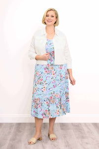 Woman posing in a blue floral dress layered with a white cropped jacket