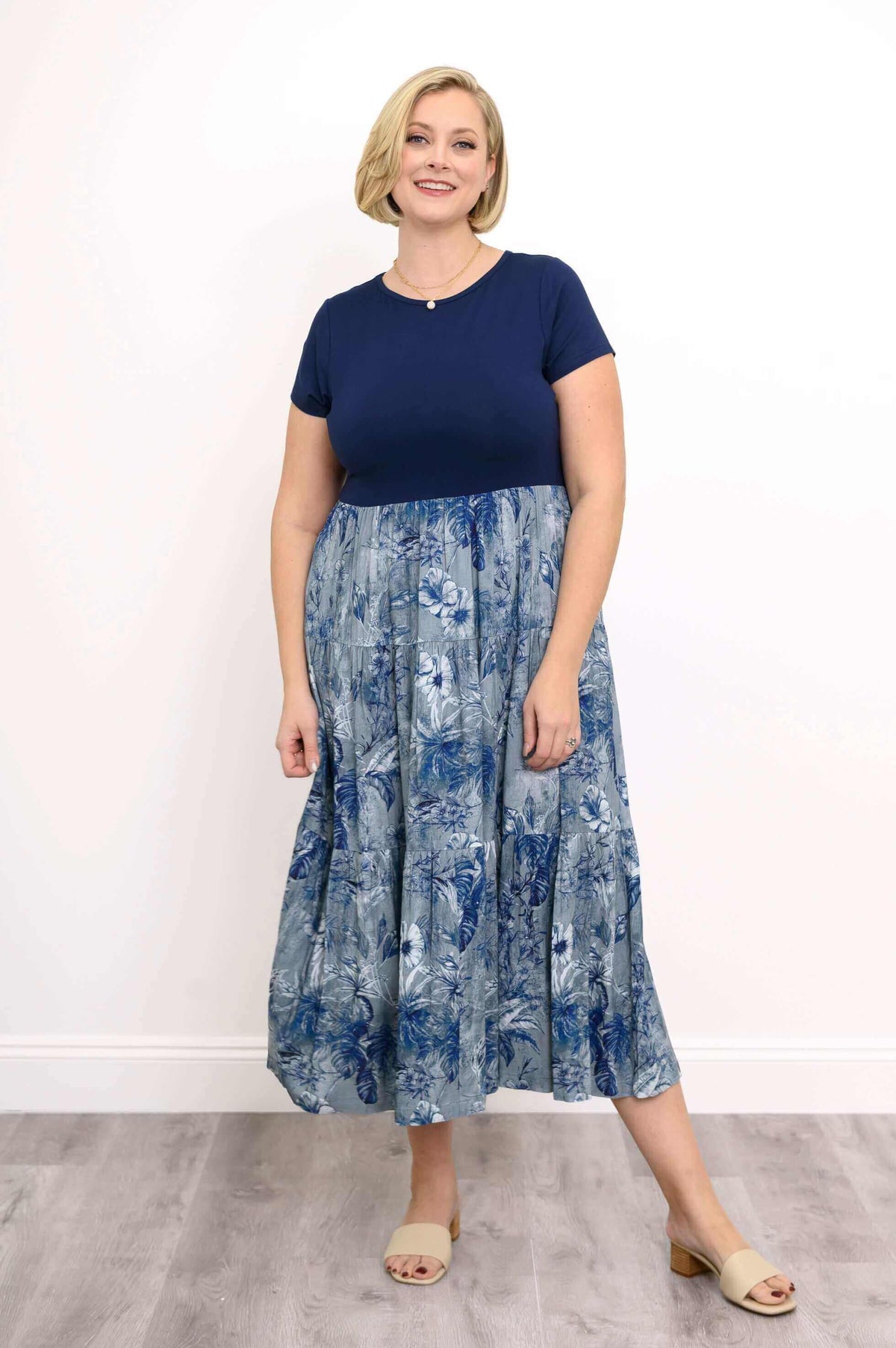 Woman smiling in a blue floral empire waist dress with short sleeves