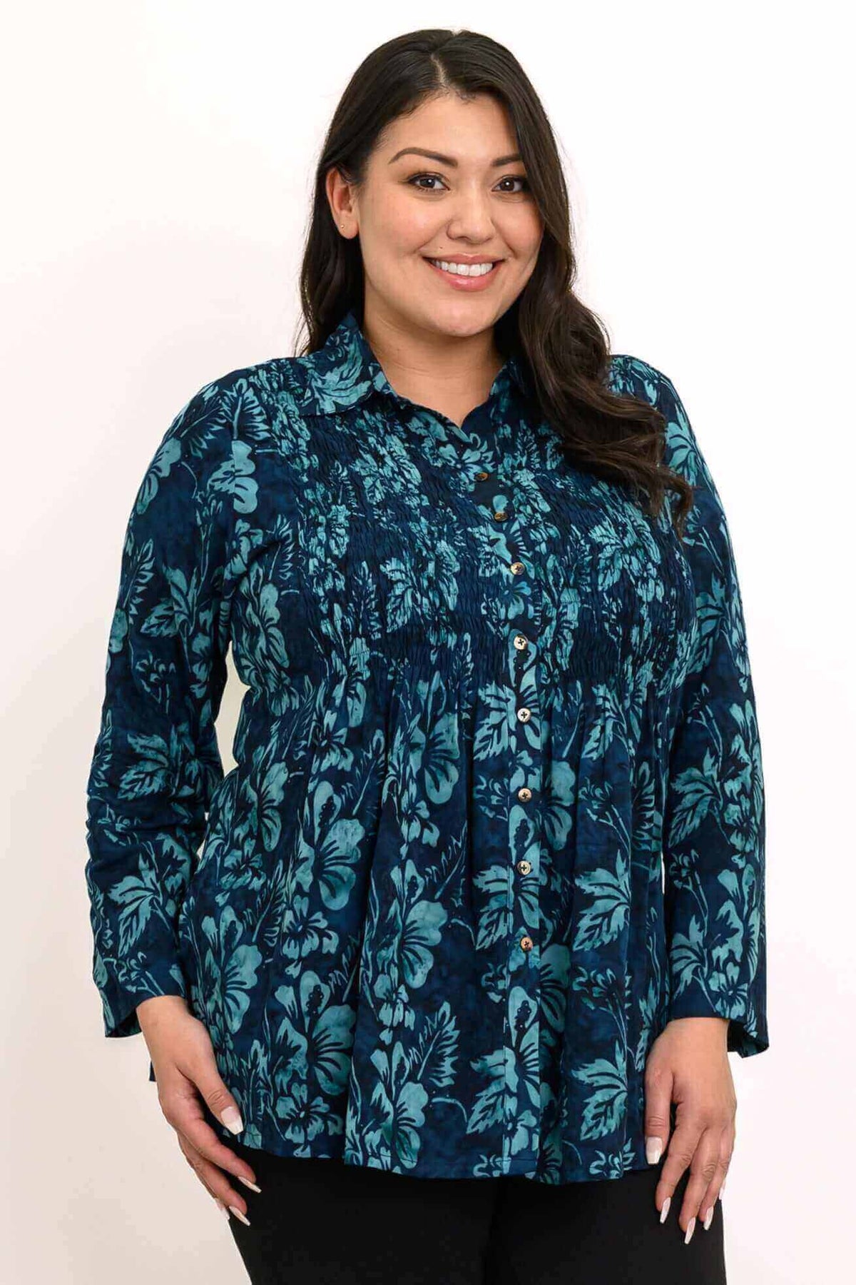 Woman wearing a blue floral long sleeve blouse with button front and smocked bodice, smiling