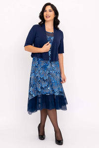 Woman posing in blue floral mesh dress with matching navy shrug