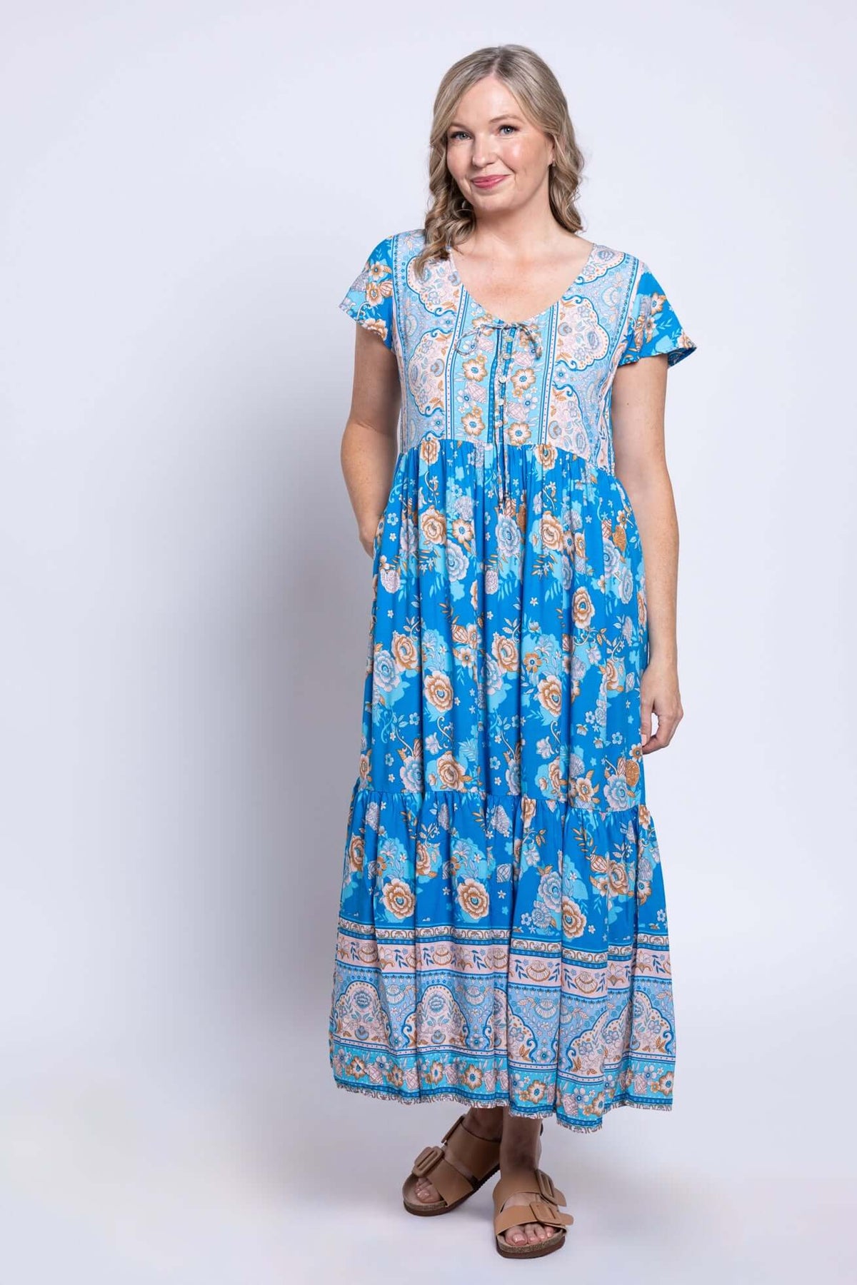 Woman modeling a blue floral midi dress with front buttons and pockets, front view