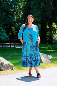 Woman outdoors in a blue floral midi dress with a matching cardigan, standing on a path