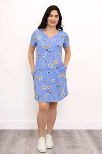 Model in blue floral shift dress with hands in pockets and white sneakers