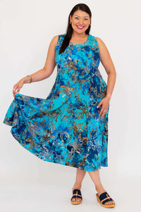 Woman displaying the flared skirt of a blue floral sleeveless midi dress, posing against a white background