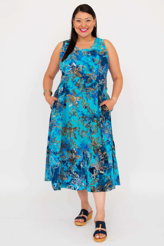 Woman wearing a blue floral sleeveless midi dress with pockets, standing against a white background