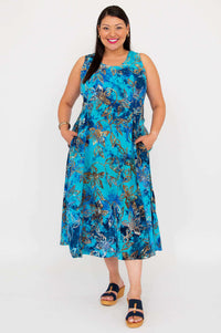 Woman wearing a blue floral sleeveless midi dress with pockets, standing against a white background
