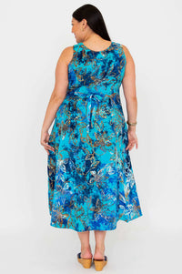 Back view of a woman in a blue floral sleeveless midi dress with a tie-belt, standing against a white background