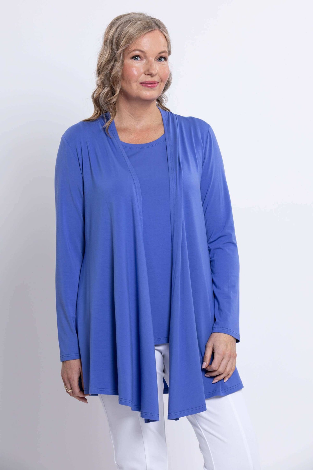 Woman wearing a long sleeve blue open front jacket with white pants, close-up view