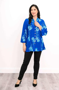 Woman posing in a blue floral mandarin collar blouse with black pants