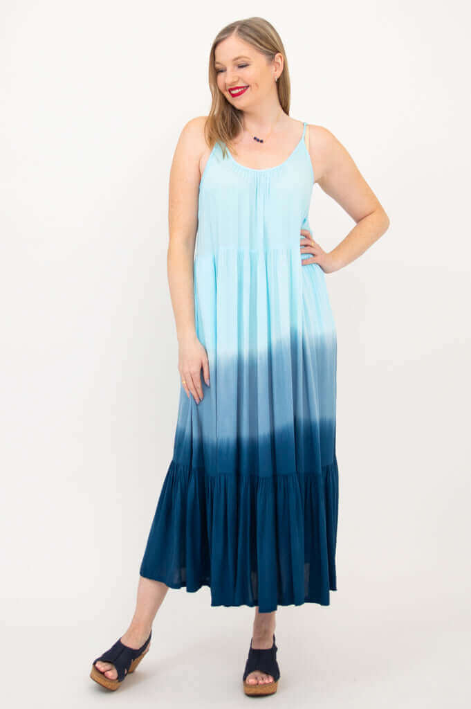 Woman standing and smiling in a blue ombre maxi dress, hand on hip