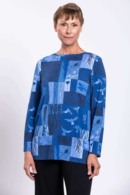 Woman wearing a blue patchwork long-sleeve top with a boat neckline, upper body view