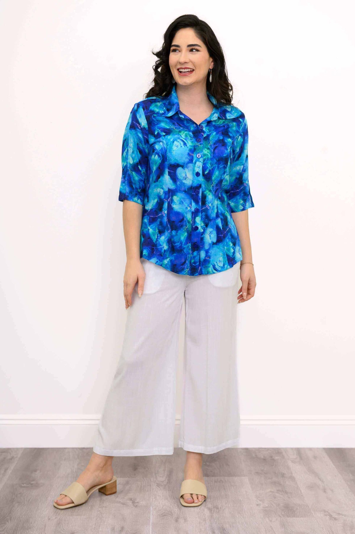 Model in a blue patterned blouse with white wide-leg pants