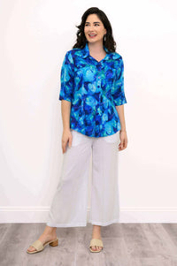 Model in a blue patterned blouse with white wide-leg pants