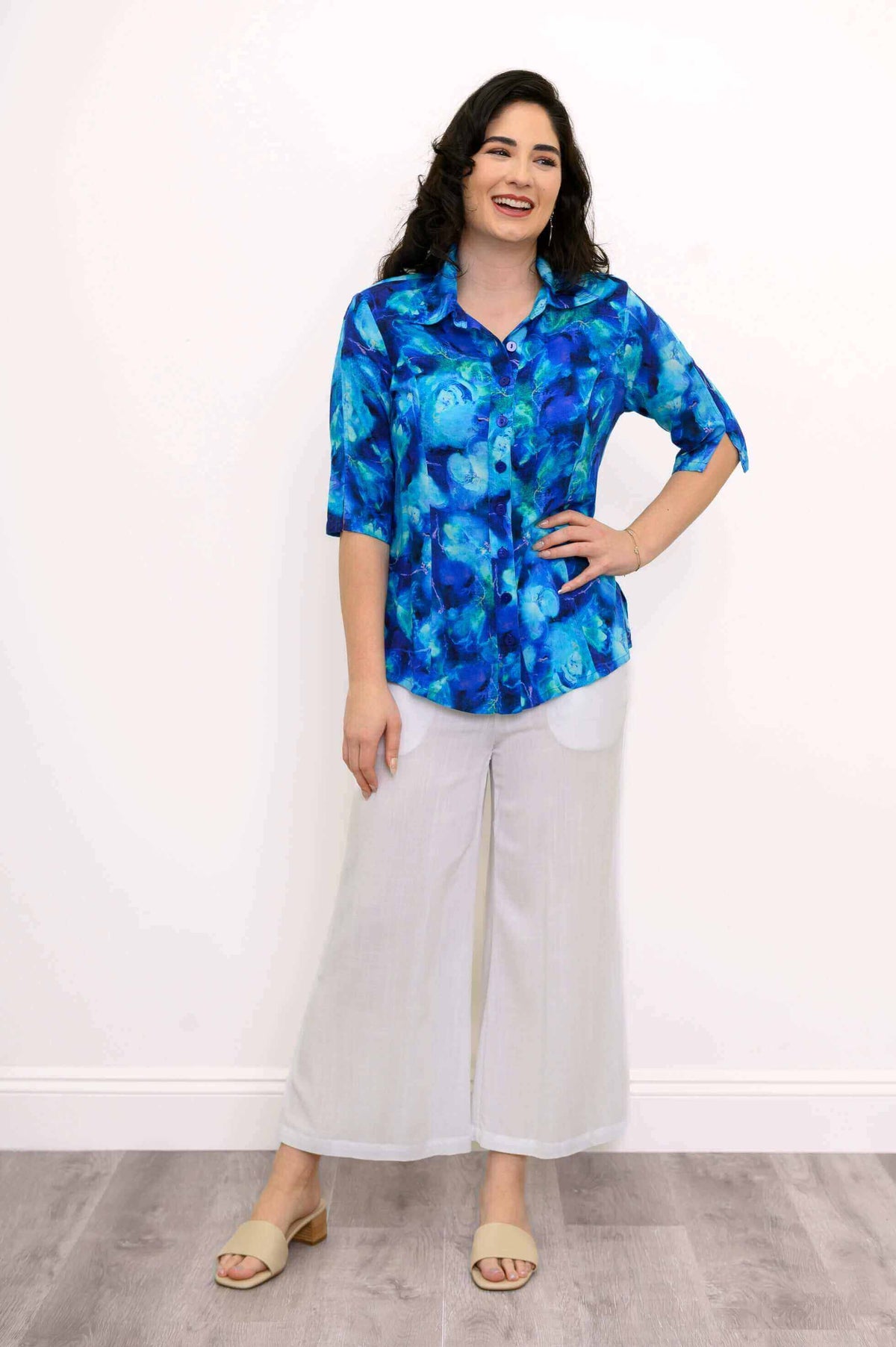 Model in a blue patterned blouse paired with white wide-leg pants