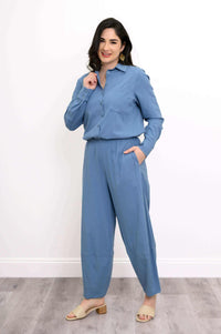 Woman in blue outfit with shirt tucked into elastic waist wide-leg pants, hand in pocket