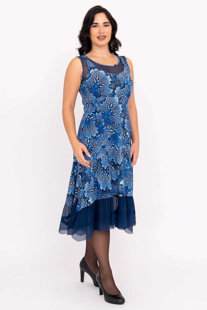 Woman wearing a blue sleeveless mesh dress with floral patterns and layered hem