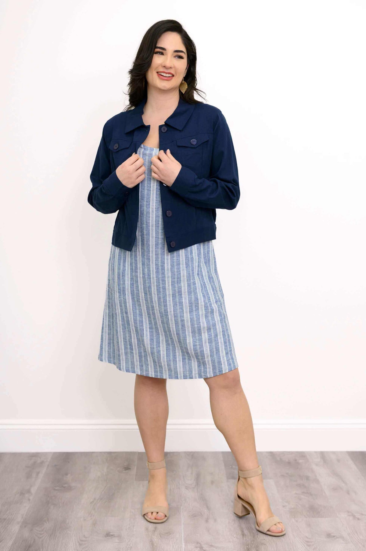 Woman in blue striped shift dress with navy jacket, smiling