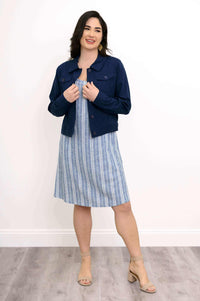 Woman in blue striped shift dress with navy jacket, smiling