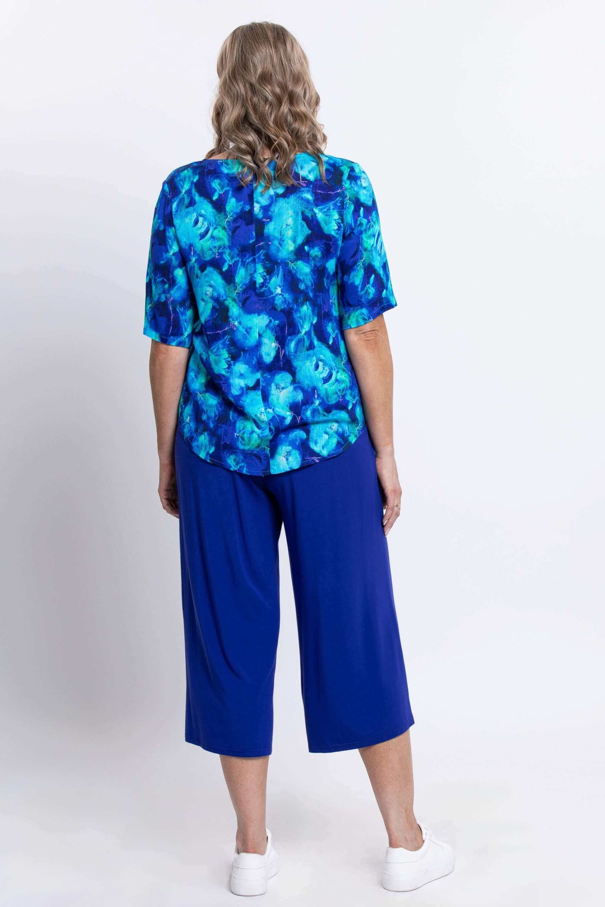 Back view of woman in blue watercolor blouse and blue pants