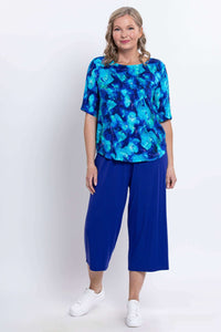 Woman posing in blue watercolor blouse and blue wide-leg pants, angled front view