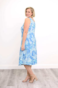 Woman in a blue watercolor tank dress, angled side view smiling over shoulder
