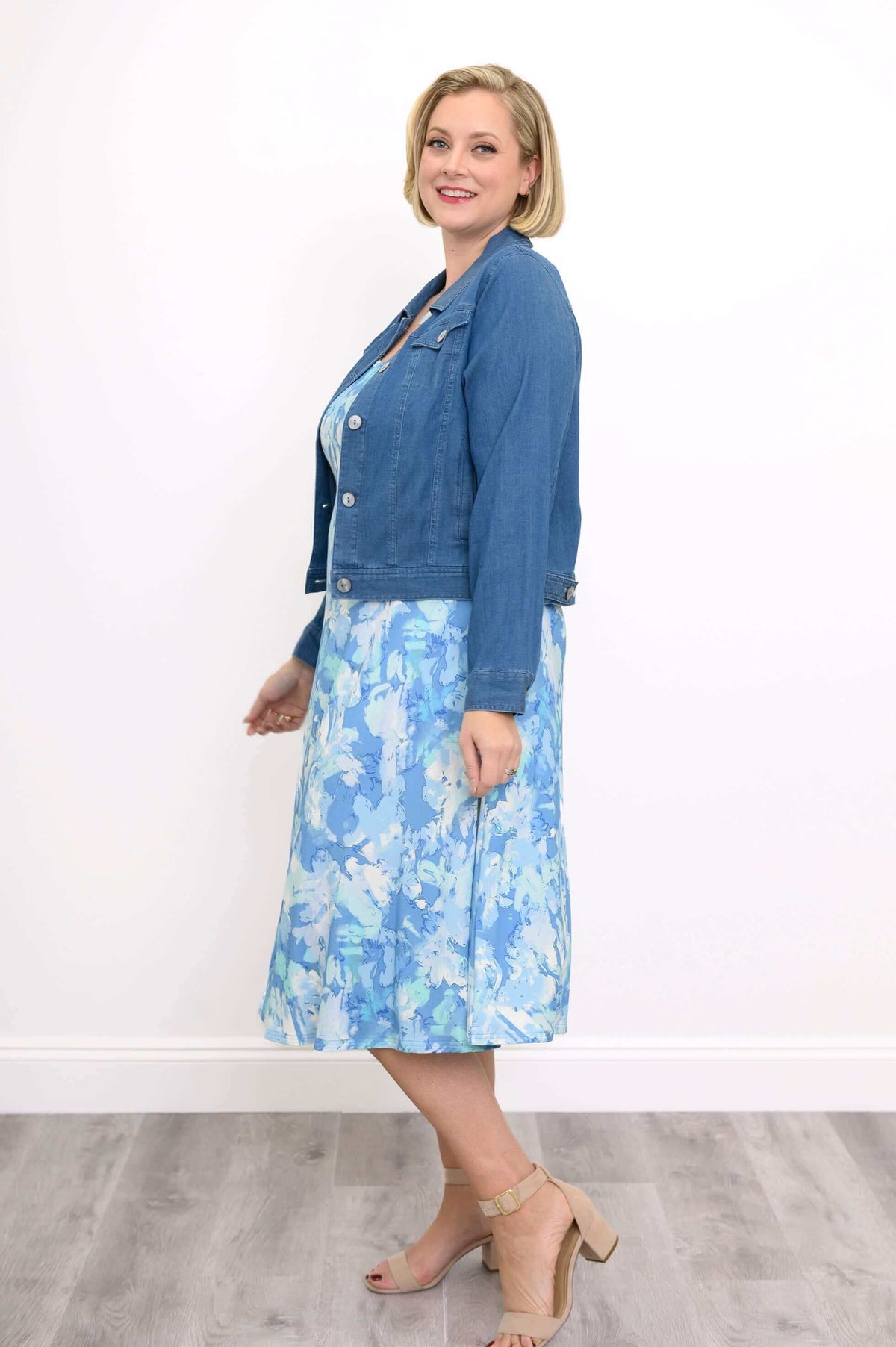 Woman in a blue watercolor tank dress paired with a blue denim jacket, side view