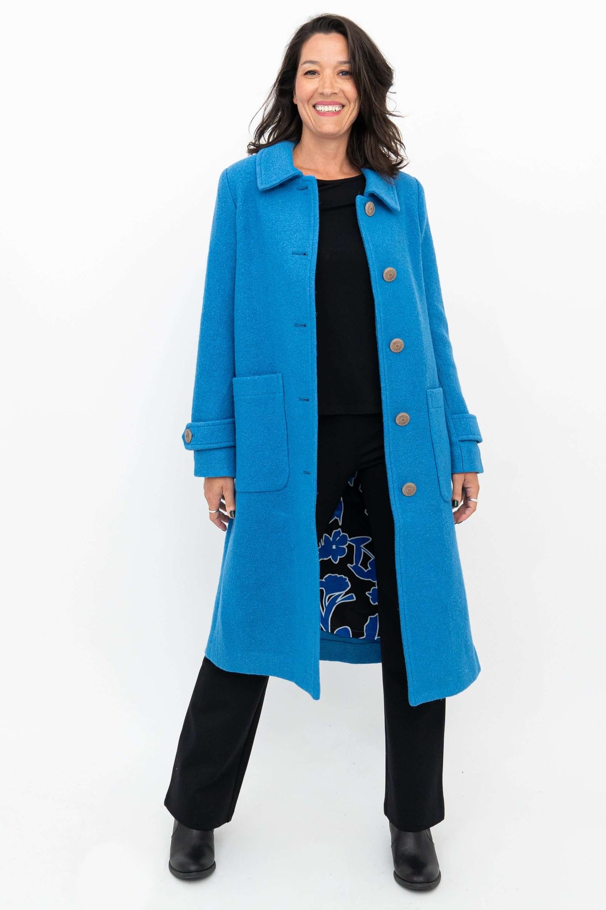 Woman modeling a blue wool coat, opened to show a floral print lining