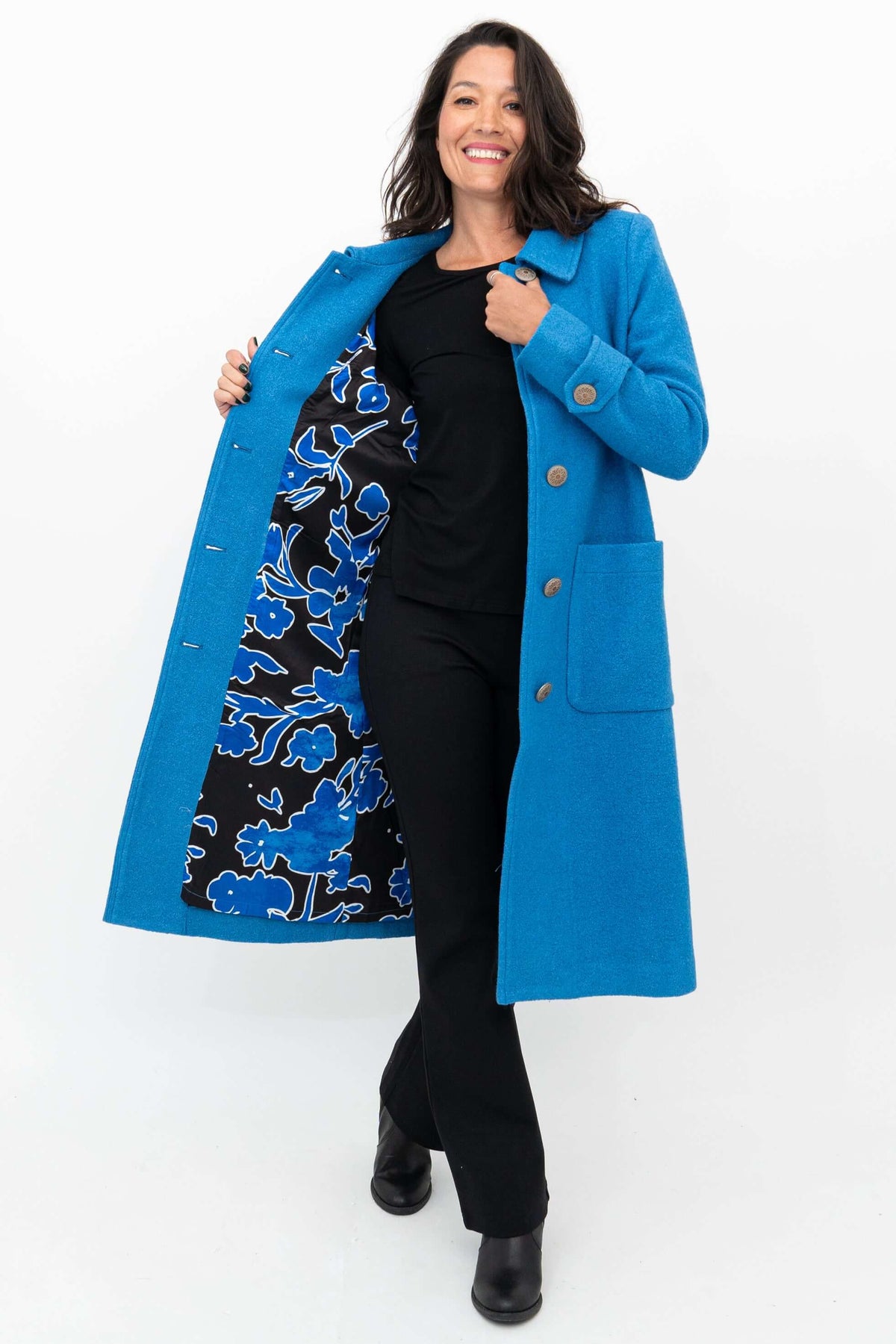 Woman smiling and holding open a blue wool coat to reveal the floral lining