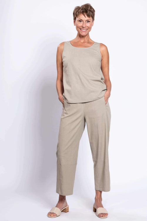 Woman wearing cropped beige Boardwalk Pants and matching sleeveless top, front view, hands in pockets