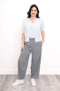Woman wearing boardwalk black gingham barrel-leg pants styled with a white cardigan and sneakers