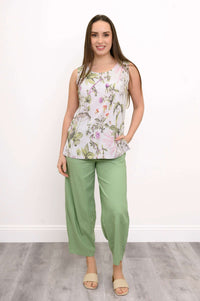 Full body view of a woman in a floral sleeveless tank top and green pants