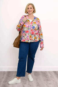 Woman holding a brown bag, dressed in a pink floral hoodie jacket with jeans and white sneakers