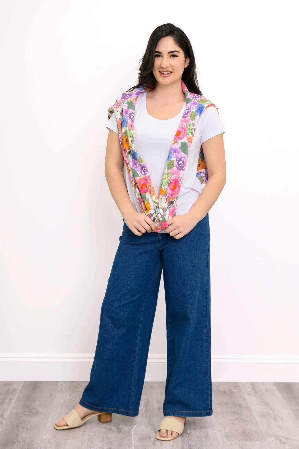 Woman with floral hoodie draped over her shoulders, wearing a white shirt and blue jeans