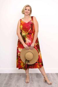 Front view of sleeveless midi dress with vibrant sunset abstract print, model holding beige sun hat