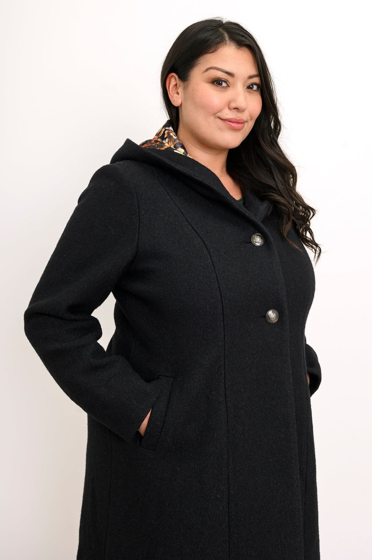 Close-up side view of woman wearing black boiled wool coat with pockets and silver buttons
