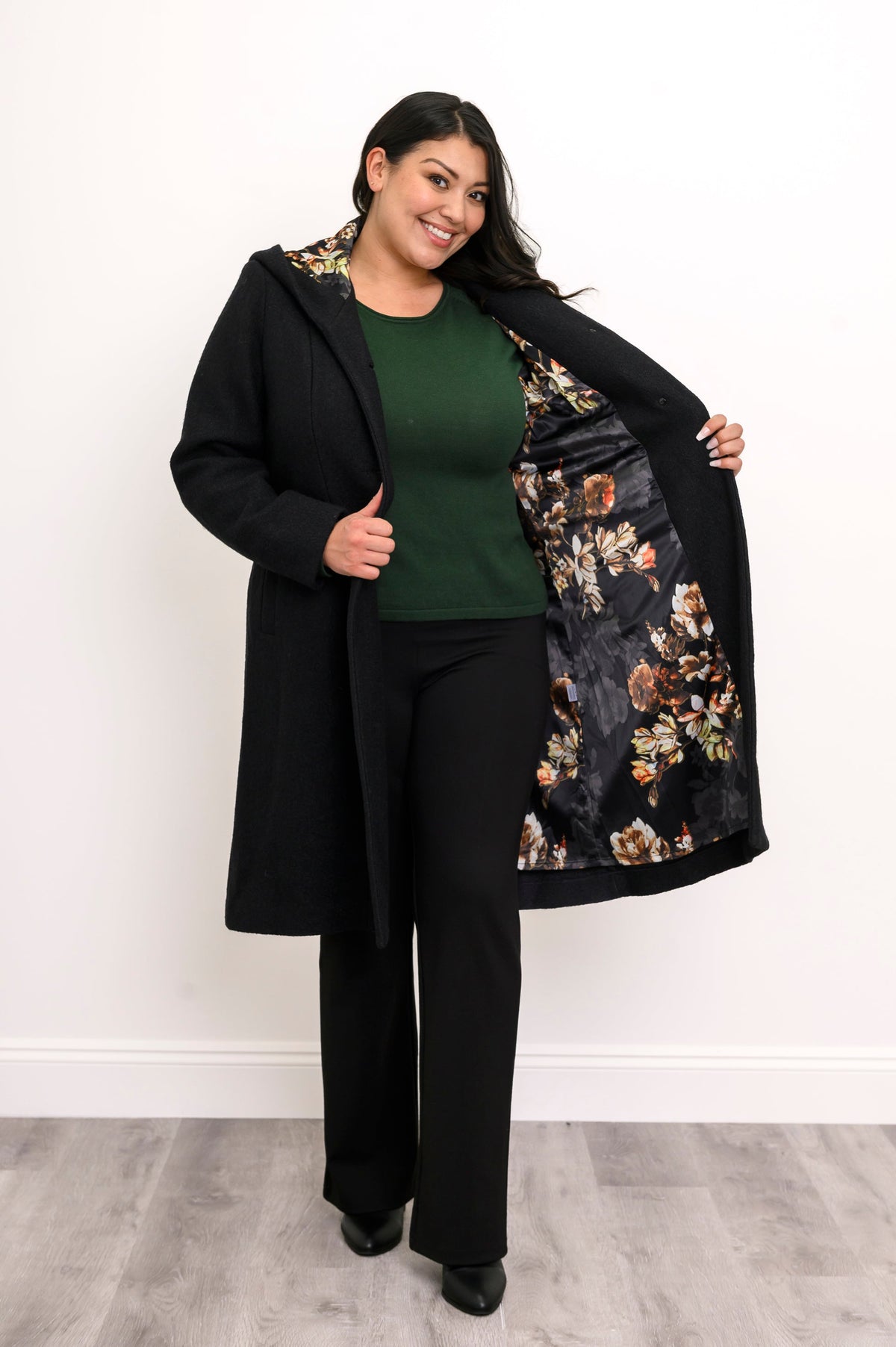 Woman showing off the black and multicolor floral satin lining of her long black coat